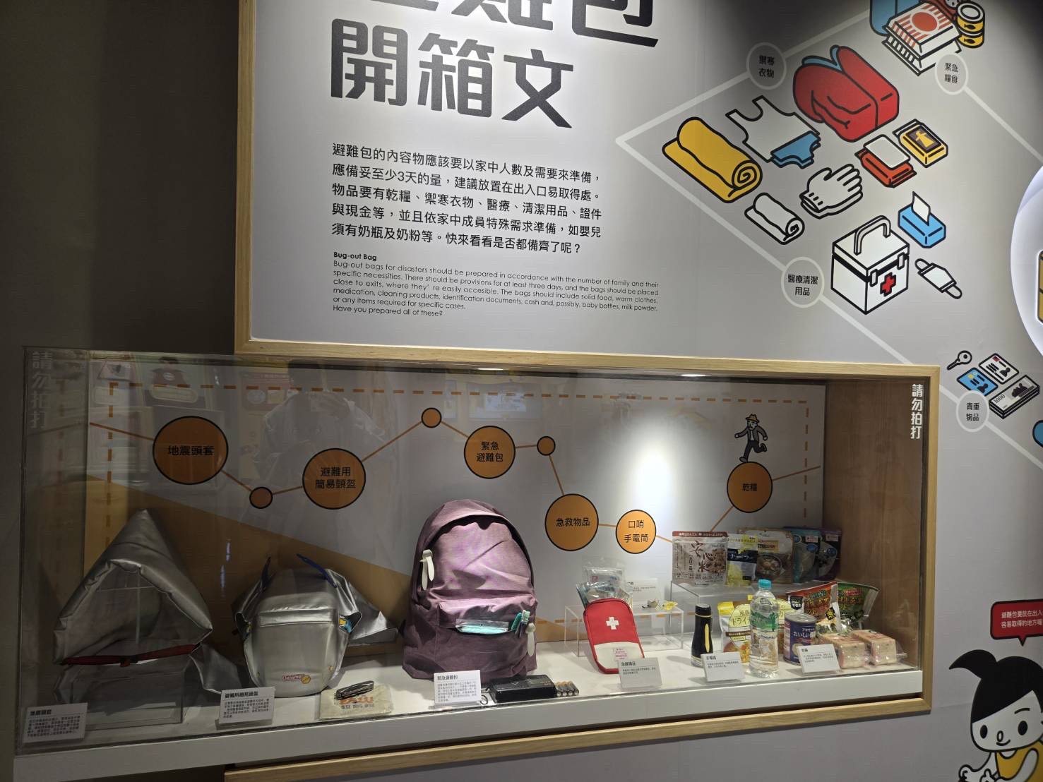 486團購生活推薦：展館內緊急避難包開箱文展示櫥窗，陳列地震頭套、急救用品與乾糧等必備防災物資。